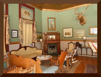 Victorian parlor with paintings on walls and a mounted deer head
