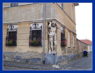 Carved statue appearing to hold up the corner of a building, Nitra.