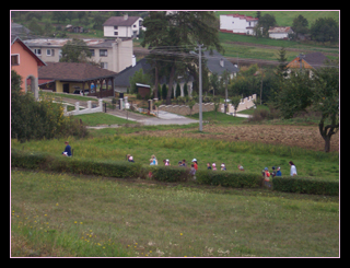 Schoolchildren with their teacher walking along a path beneath the cemetery,
Gregorovce