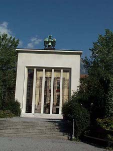 The monument is sharply rectangular, with square granite pillars in front of a square window against a square front face; on top is a green bronze eagle