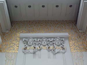 The white door to the Secession Building is decorated with carved white Medusas and a gilt leafy background