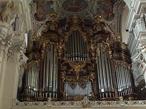 The organ pipes are situated in a rococo alcove with gold trim against a white lacy surrounding