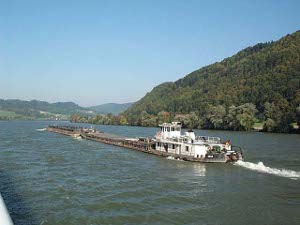 One push boat with two attached barges heading up the Danube passes our cruise boat