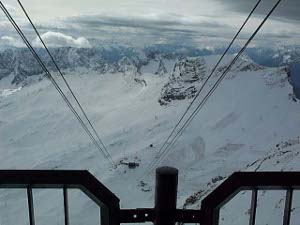 Looking down from the gondola station at the cables, against a background of snowy mountains