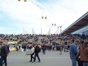 Masses of people spread over a larged paved tarmac at the Hannover Expo, stopping at small vendors of refreshments