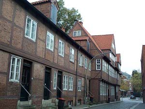 A row of old red brick houses with the higher stories overhanging the lower