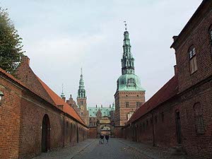 A long street flanked by red brick buildings leads up to the first gate leading to the castle