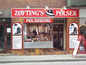 Zofting's Polser, says the sign, with slashes through the o's, and sausages are hung and laid out behind the large plate glass window, flanked by cartoons of a butcher in a white jacket and black hat.