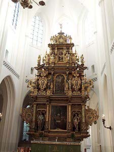 Against the plain white walls the ornate gilt altar with carvings of holy figures presents a striking contrast