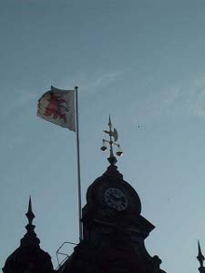 Atop the Rathaus cupola is a clock and the scales of justice and a crossed spear and axe, along with the Swedish flag, all silhouetted against a blue sky