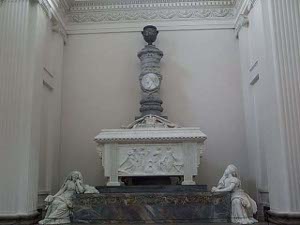 The white marble tomb sits aon a platform with female figures sculpted at the base; a large column tops the tomb