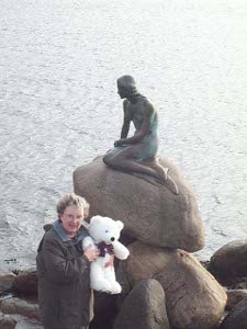 Elsa holds Cuddles in front of the statue of the Little Mermaid which is atop a rock