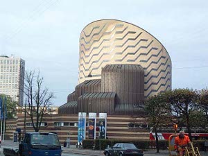 Built in the shape of a truncated cylinder with a slanting roof and large zig zag lines, with subordinate parts of the structure in dark brown bracing up the cylinder, the planetarium is a commanding Copenhagen landmark