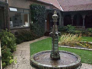 The tile-roofed building surrounds a small garden courtyard with a fountain
