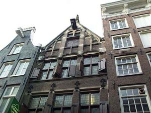 A typical four story Amsterdam building with a strong hoist extending from the top floor over the sidewalk to lift heavy items of furniture