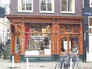 The bottom floor of a red brick building houses a store with elaborate carved and varnished wood and bicycles parked in front