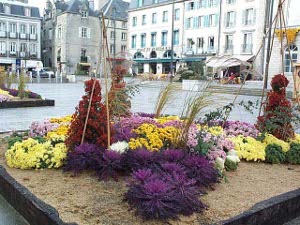 The square is glistening from a rain shower, and in the foreground is a most elaborate and flashy display of flowers with yellow, orange red, deep purple, and gray green sea grasses