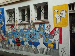 The side of the building is painted in bright colors with cartoon family figures sitting around a large table at a banquet of some kind