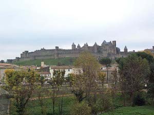 The magnificent walled city is visible on a hilltop, surrounded by green fields and overlooking the modern town