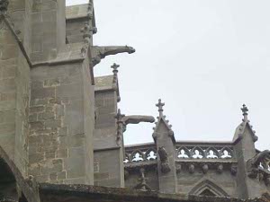 A lovely gray stone gothic building with gargoyles along the roof