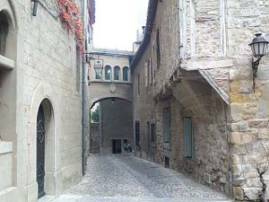 the second floor of buildings overhang the street, and a gallery passage connects houses across the narrow cobblestone street