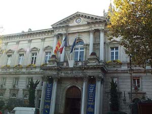 Flags fly in front of the two-story city hall in Avignon