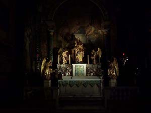 Praying angels surround the image of Mary; only the altar is illuminated.