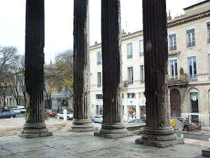 The photograph captures four of the stone columns surrounding the porch of La Maison Carree.  These are eroded and blackened, but still erect after 2000 years.
