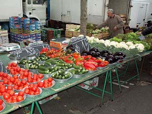 Tomatoes, Cauliflower, peppers, eggplant, zucchini, broccoli are laid out in small dishes for sale on several temporary market tables
