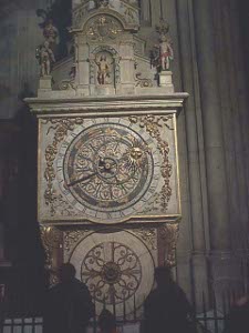 The clock is beautifully decorated and is set behind a black iron fence inside the cathedral.