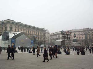 The big square where the Milan Cathedral is located is enormous.  There are some temporary structures in place, and people in dark clothing are walking in every conceivable direction across the square