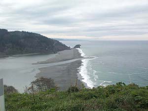 A narrow channel cuts through the barrachois, a wide gray sand bar at the mouth of the Klamath River