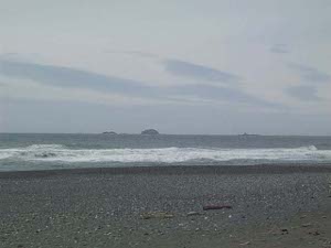 The beach has a dark gray rocky surface; the day was cloudy and the whole picture is somewhat gloomy