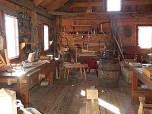The well-lit carpenter shop features 19th century hand tools for woodworking, along with numerous woodworking benches