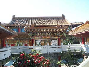The architecture is traditional chinese with sloped ornamented roofs and brightly lacquered walls and fences