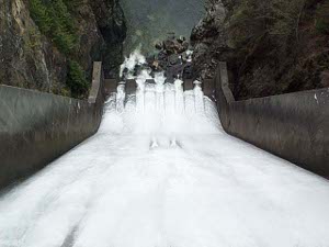 Looking down the spillway to the foaming white water at the bottom emptying into the narrow dark stone gorge