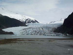 The glacier, a striated valley of dirty looking ice, stretches down to the waters edge where small icebergs calve off