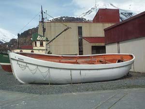 A seaworthy lifeboat rests on the shore in Valdez harbor