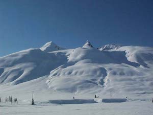The mountain is entirely covered in snow, and looks like a winter decoration, with piles and heaps of rounded, snow covered shapes