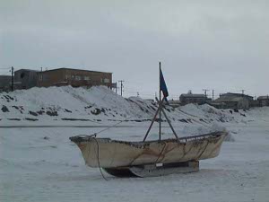 The small boat is covered with animal skins; it is pushed across the ice on a wooden sledge to reach the water