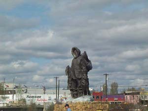 The sculpture appears to be around 20 feet high, and depicts a man in a hooded anorak and his family