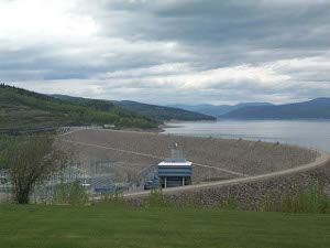 The dam is shaped somewhat like the letter J across the Peace River.  A reservoir is upstream and a power plant below
