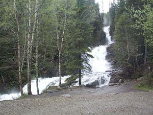 The waterfalls cascade from ledge to ledge, tumbling down a series of shelves amid the evergreen forest