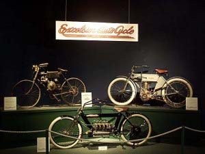 Three Excelsior motorcycles displayed on museum stands