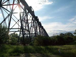 Built of black iron in a triangular grid, the railroad bridge passes high in the air to stay away from flood waters