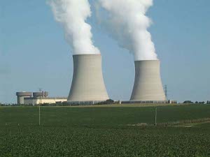 shaped like frustrums of a cone, the grey cement cooling towers give off clouds of steam