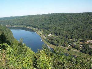 The view from the overlook shows the river winding through heavily forested green hills, with a small settlement along the shore.