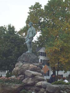 The Minuteman, also sculpted in bronze, stands with his left leg extended forward, his musket lying across his thigh