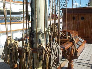 On the deck of an old sailing ship, well cared for, at the base of the mast, is a taff rail with ten or more lines descending from the mast and fixed to belaying pins