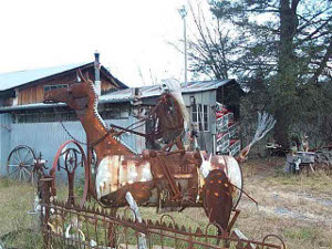 The metal sculpture is rusty with age, and depicts a skeleton rider on a large metal horse